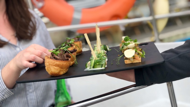 Passenger being offered canapes whilst sailing in Auckland